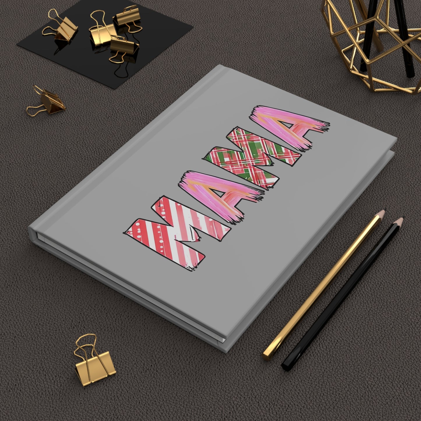 Gray hardcover journal with the word “MAMA” in large letters, each filled with holiday-themed patterns including pink brushstrokes, red and green plaid, and candy cane stripes.