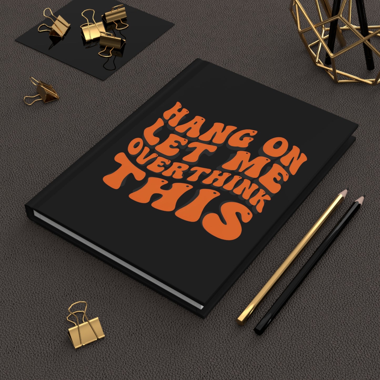 Hardcover journal with a black cover and bold orange retro-style text that reads “Hang On Let Me Overthink This.”