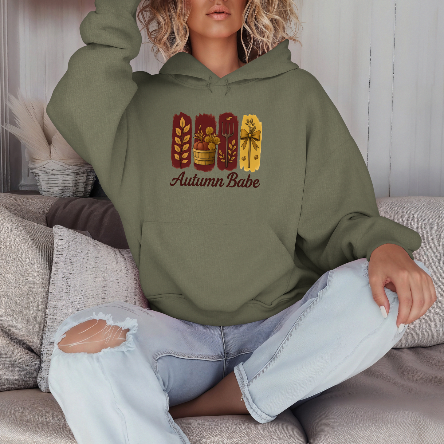 Person wearing a green hoodie with 'Autumn Babe' design sitting on a couch.
