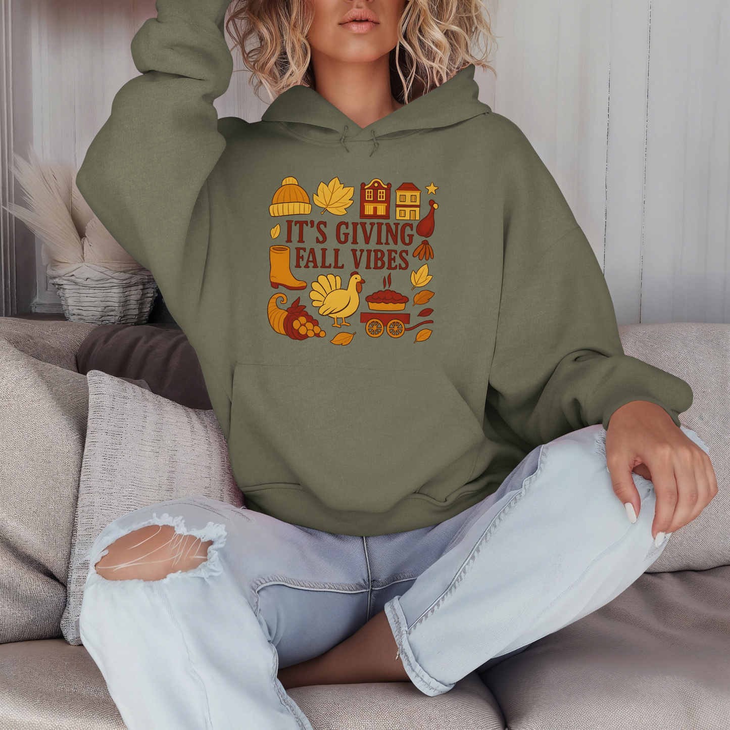 Person wearing a green hoodie with fall-themed design sitting on a couch.