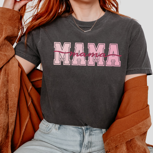 t-shirts with bold pink “MAMA” block letters and cursive script overlay, available in black, slate blue, sage green, charcoal, and ivory colors